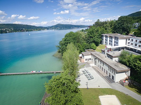 Das Sonnencamp Sekirn befindet sich direkt am Südufer des Wörthersees. Das Ferienhaus hat direkten Seezugang. die großzügige Freizeitanlage verfügt über einen großen eigenen Strand mit mehreren Steganlagen und zahlreichen Sportmöglichkeiten Das Foto zeigt das Ferienhaus Sonnencamp Sekirn aus der Vogelperspektive. Links im Bild einer der Stege mit direktem Seezugang zum Wörthersee und die Liegewiese